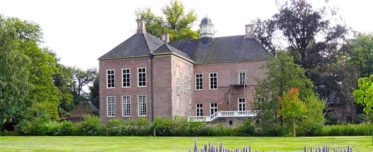 Large brick house with a lawn and mature trees