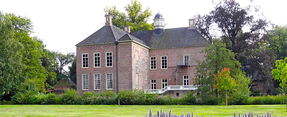 Large brick house with a lawn and mature trees