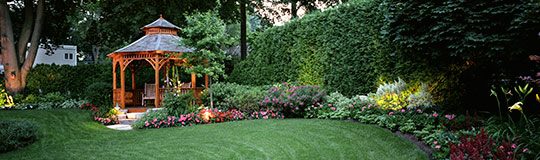 Landscaped backyard with a wooden gazebo, lawn and flower beds