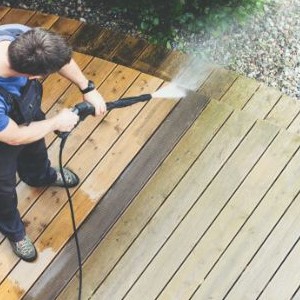 Worker power washing a wooden deck